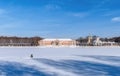 A fisherman sits on the ice of a large palace pond and catches fish.